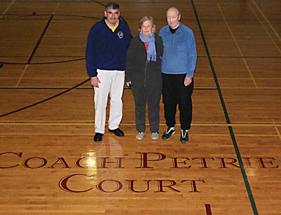 Coach Ed Petrie, the state’s winningest public high school boys basketball coach, his wife, Nancy, and Joe Vas, left, the East Hampton School District’s athletic director, admired the new “Coach Petrie Court” logo at the high school.