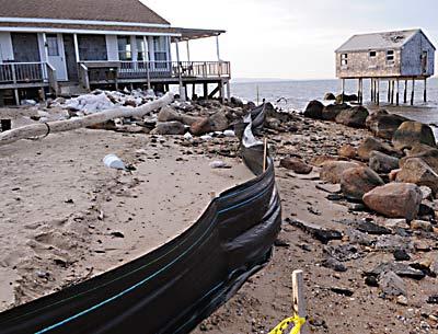 A house at the end of Mulford Lane at Lazy Point, which now is on the beach, may be demolished and rebuilt elsewhere on the property. A house on posts in the water at right shows just how far the shoreline has eroded.