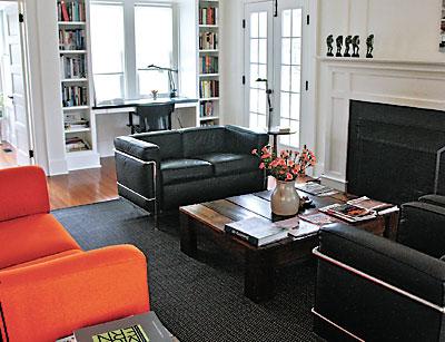 An orange sofa by Piero Lissoni and a love seat and chairs by Le Corbusier provide seating around the coffee table, which the couple built from a wooden container they found in the basement.