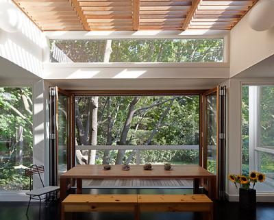 The dining room, with a folding door and a screen that comes down from the ceiling, opens to a deck. The partners made the table themselves.