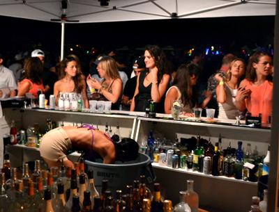 A bartender, above, at the Shark Attack party held at the Montauk Yacht Club Friday night dived deep into a cooler for refreshments for some of the estimated 3,400 guests.