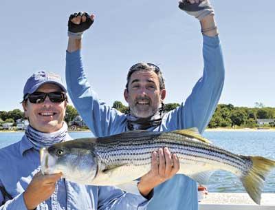 Chris Lanning, arms raised in celebration, caught this 35-inch striper in three feet of water off of Shelter Island last week while fishing with his guide Brendan McCarthy.