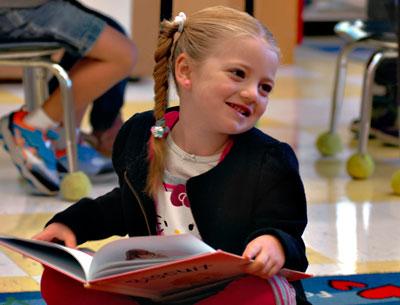 Grace King, who just turned 5, enjoyed a book while other students in Kristin Tulp’s kindergarten class practiced using scissors and glue.