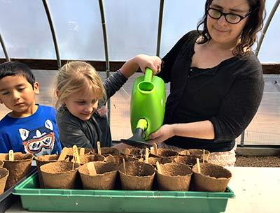 Hailey London, right, led kindergarten students in a lesson on planting and watering in the Springs School greenhouse. Ms. London is the school’s greenhouse manager and garden educator.