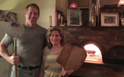 Nancy Hollister and her husband, Owen Jander, who put an addition onto their small Springs house to accommodate the oven, pose as guests arrive for a bimonthly pizza party.