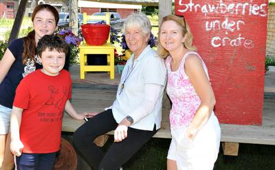 Mary Heilmann, center, met up with a family visiting from Ireland at Robert and Joanne Comfort’s farm stand in Bridgehampton on Saturday. One of her chair sculptures and a ceramic bowl of hers are displayed behind them.