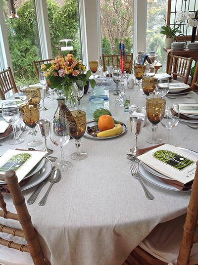 The table is set for last year’s Seder. The artichoke, orange, and banana on the second Seder plate are symbols of contemporary life, and a child’s death.