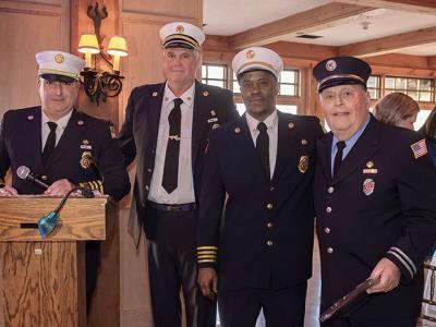 Ken Wessberg, second from left, who just finished another term as East Hampton Fire Department chief, handed the reins over to the newly elected chief, Gerry Turza, at the lectern. At right are First Assistant Chief Jamalia Hayes and William Bennett, who was recognized Saturday night for 55 years of service.