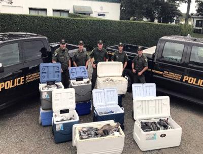 State D.E.C. officers with some of the estimated 1,000-plus fluke and sea bass they seized after checking a party boat in Lake Montauk on Aug. 31. The fish were donated to charity, according to a D.E.C. spokeswoman.