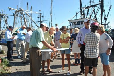 Harry Dodson of the planning firm Dodson and Flinker, at left in the green shirt, held a map of Montauk's dock area while participants in a walking tour there yesterday talked about problem areas and opportunities for improvement. Behind him with the note pad was his partner, Peter Flinker.