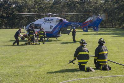 Firefighters stood by with a charged hose line as a precaution while other firefighters and E.M.T.s moved a patient to the Suffolk County medevac helicopter on Saturday.