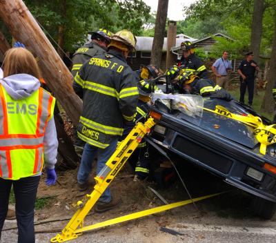 The Springs Fire Department worked to extricate two people from a Porsche that crashed into a utility pole on Three Mile Harbor-Hog Creek Road on Saturday afternoon.