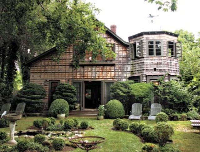 The roofline angles that lured Diane Blell, and the turret she added, overlook the all-green garden. Below, from left: An ormolu-framed mirror adds sparkle to a niche, and Planet the cat guards the entrance to the living room.