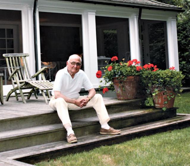 The architect is seen on the stadium steps at the back of the house, which looks out on the garden.