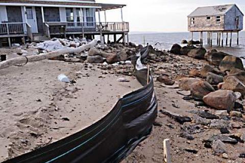 A house at the end of Mulford Lane at Lazy Point, which now is on the beach, may be demolished and rebuilt elsewhere on the property. A house on posts in the water at right shows just how far the shoreline has eroded.