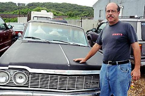 Tom Ferreira, outside his house on Navy Road in July of 2010, says the town illegally removed vehicles from his property, added the $19,700 hauling cost to his taxes, then placed a lien on his property when he couldn’t pay.