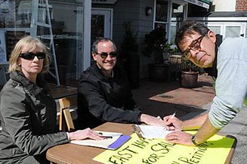 Pamela Bickett and Zachary Cohen, who narrowly lost a bid for town supervisor in November, collected signatures on Monday to force the town board to put a contested sale of public property to a townwide vote. Greg Turpan got ready to sign.