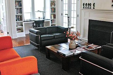 An orange sofa by Piero Lissoni and a love seat and chairs by Le Corbusier provide seating around the coffee table, which the couple built from a wooden container they found in the basement.