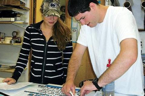 Jacqulene Albright-Kehoe, whose father, Jack Kehoe, opened Sign Language in 1979, looked over lettering being done by her cousin Sean Kehoe.