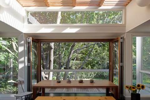 The dining room, with a folding door and a screen that comes down from the ceiling, opens to a deck. The partners made the table themselves.