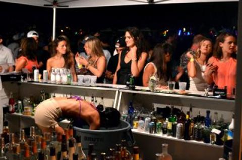 A bartender, above, at the Shark Attack party held at the Montauk Yacht Club Friday night dived deep into a cooler for refreshments for some of the estimated 3,400 guests.