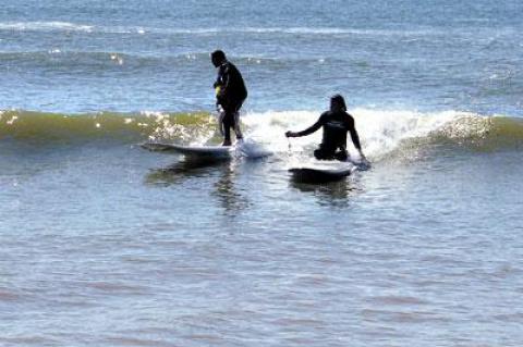 During the Surfers Healing event for autistic children in Montauk on Friday, Israel Paskowitz, seated on the board at right, filmed one of the young participants as she rode a gentle wave with her helper.