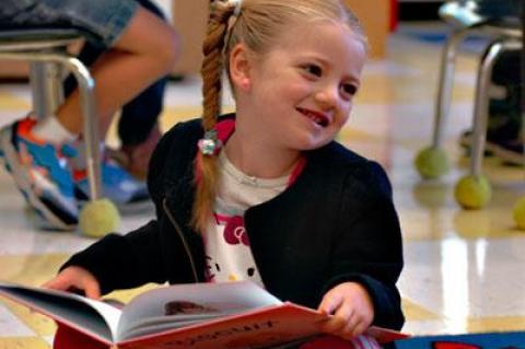 Grace King, who just turned 5, enjoyed a book while other students in Kristin Tulp’s kindergarten class practiced using scissors and glue.