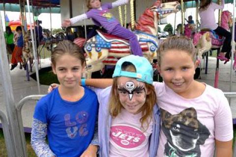 Maisie Noll, Sofia Nagle, and Maggie Nordlinger posed for a photo as Nina D’Agostino rode by on the carousel.