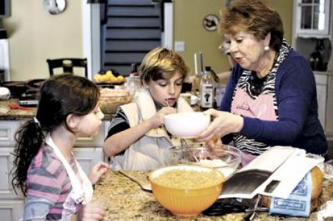 Toby Spitz explained the fine points of latke-making to Siena Link-Morse and Julian Link-Morse on Sunday.