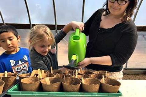 Hailey London, right, led kindergarten students in a lesson on planting and watering in the Springs School greenhouse. Ms. London is the school’s greenhouse manager and garden educator.