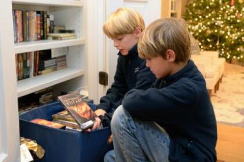 Nine-year-old Wesley Handler, left, and Colin Handler, 12, picked out the DVDs they wanted to give away as part of a community service project their father started called Santa Claustin.