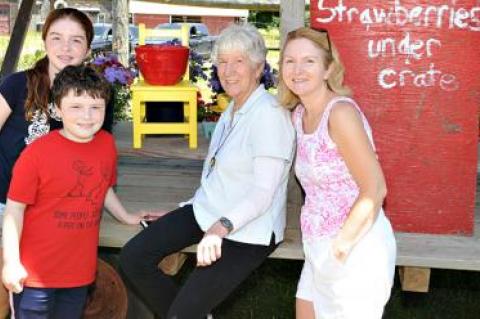 Mary Heilmann, center, met up with a family visiting from Ireland at Robert and Joanne Comfort’s farm stand in Bridgehampton on Saturday. One of her chair sculptures and a ceramic bowl of hers are displayed behind them.