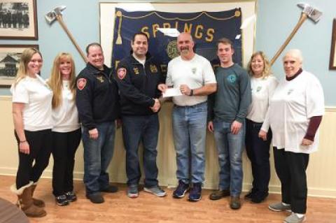 Ryan Balnis, chief of the Springs Fire Department, presented Michael Davis, captain of Team DMK for a Cure, with a check for $10,000, helping the team as it works to raise $100,000 for the Leukemia and Lymphoma Society in memory of David M. King, an ex-chief.