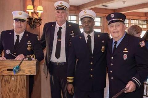 Ken Wessberg, second from left, who just finished another term as East Hampton Fire Department chief, handed the reins over to the newly elected chief, Gerry Turza, at the lectern. At right are First Assistant Chief Jamalia Hayes and William Bennett, who was recognized Saturday night for 55 years of service.