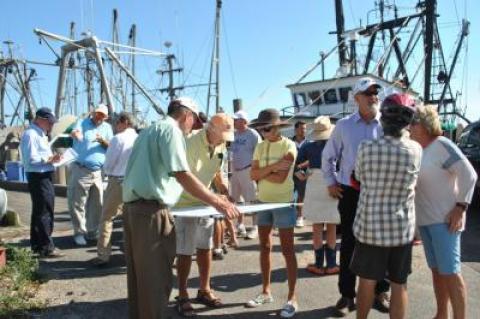 Harry Dodson of the planning firm Dodson and Flinker, at left in the green shirt, held a map of Montauk's dock area while participants in a walking tour there yesterday talked about problem areas and opportunities for improvement. Behind him with the note pad was his partner, Peter Flinker.