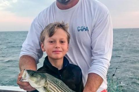 Rudy Bonicelli, first mate on the Montauk charter boat Oh Brother!, helped Timmy McKenna release a striped bass they had just caught.