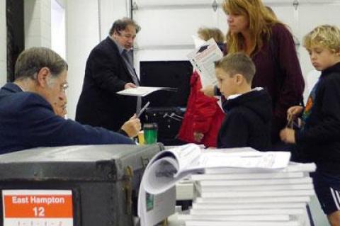 A voter, accompanied by two boys, checked in with Board of Elections poll-watchers at the Amagansett Fire House early Tuesday.