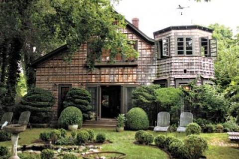 The roofline angles that lured Diane Blell, and the turret she added, overlook the all-green garden. Below, from left: An ormolu-framed mirror adds sparkle to a niche, and Planet the cat guards the entrance to the living room.