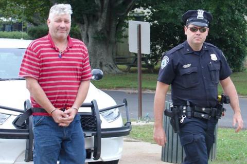 An East Hampton Town police officer led Martin Drew into Justice Court on Friday morning.