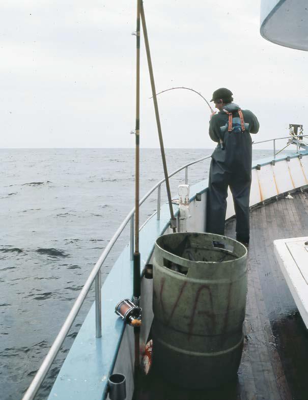 Young Fisherman. Boy in Yellow Jacket and Rubber Boots is Fishing